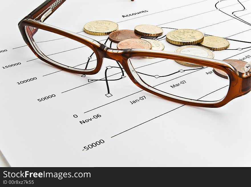 Spectacles and coins resting on financial results. Spectacles and coins resting on financial results