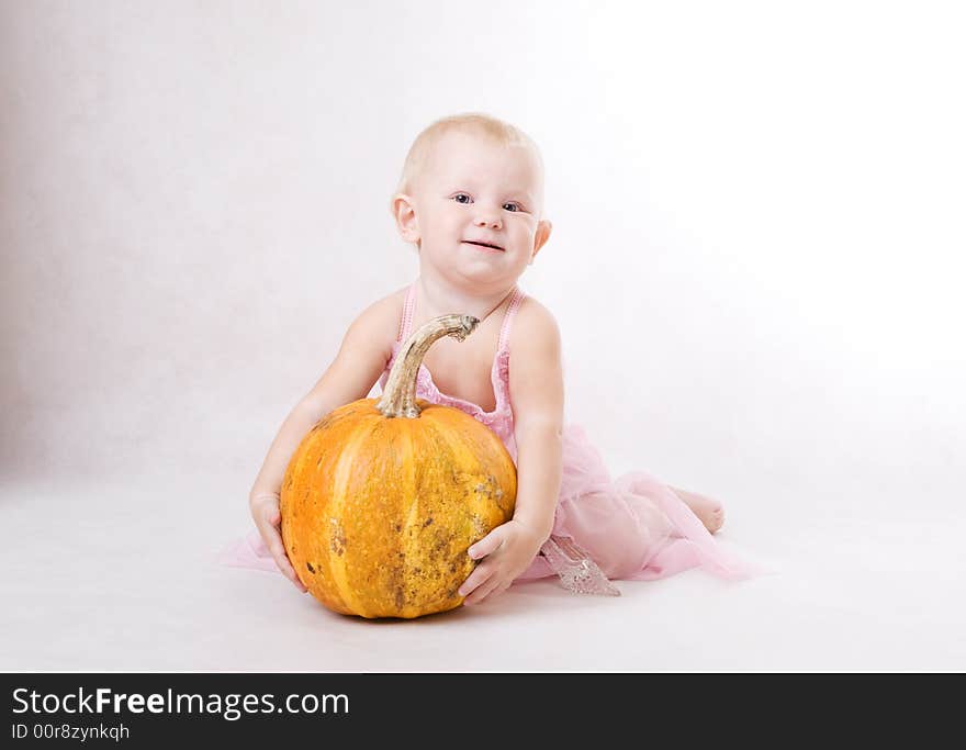 A smiling little girl embraces a pumpkin