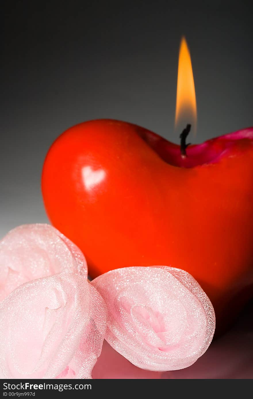 Red shape heart shining candle with pink roses. Red shape heart shining candle with pink roses