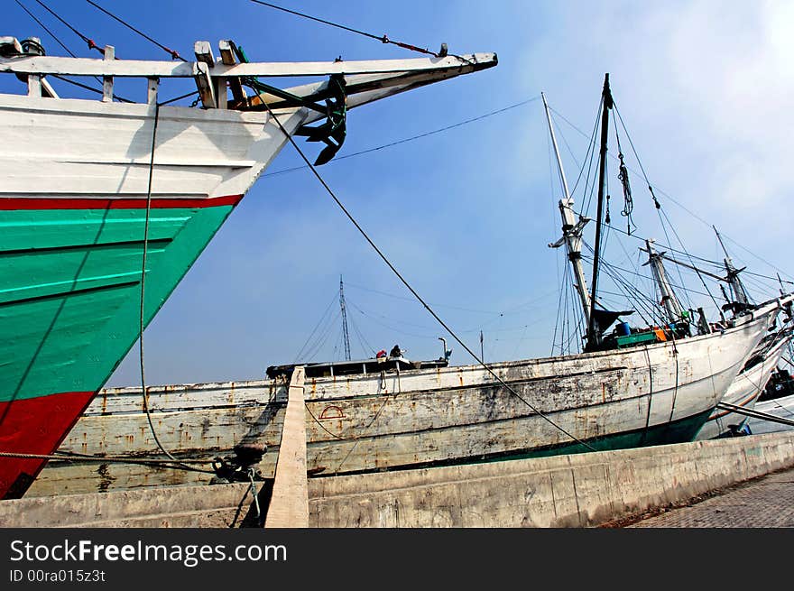 Indonesia, Jakarta: boats at Sunda Kelapa an ancient sea port; one of the most famous ports for the construction of the traditional wood boats; blue sky and colorful big wood boats. Indonesia, Jakarta: boats at Sunda Kelapa an ancient sea port; one of the most famous ports for the construction of the traditional wood boats; blue sky and colorful big wood boats