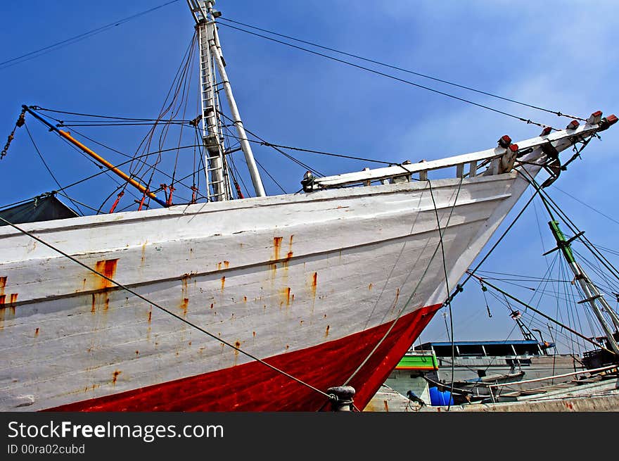 Indonesia, Jakarta: boats at Sunda Kelapa an ancient sea port; one of the most famous ports for the construction of the traditional wood boats; blue sky and colorful big wood boats. Indonesia, Jakarta: boats at Sunda Kelapa an ancient sea port; one of the most famous ports for the construction of the traditional wood boats; blue sky and colorful big wood boats