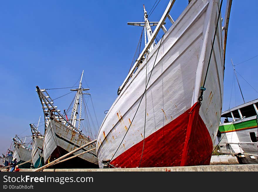 Indonesia, Jakarta: boats at Sunda Kelapa an ancient sea port; one of the most famous ports for the construction of the traditional wood boats; blue sky and colorful big wood boats. Indonesia, Jakarta: boats at Sunda Kelapa an ancient sea port; one of the most famous ports for the construction of the traditional wood boats; blue sky and colorful big wood boats