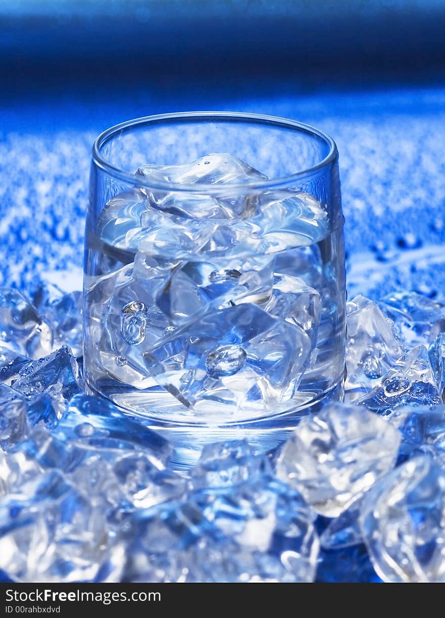 Glass with water and ice over blue