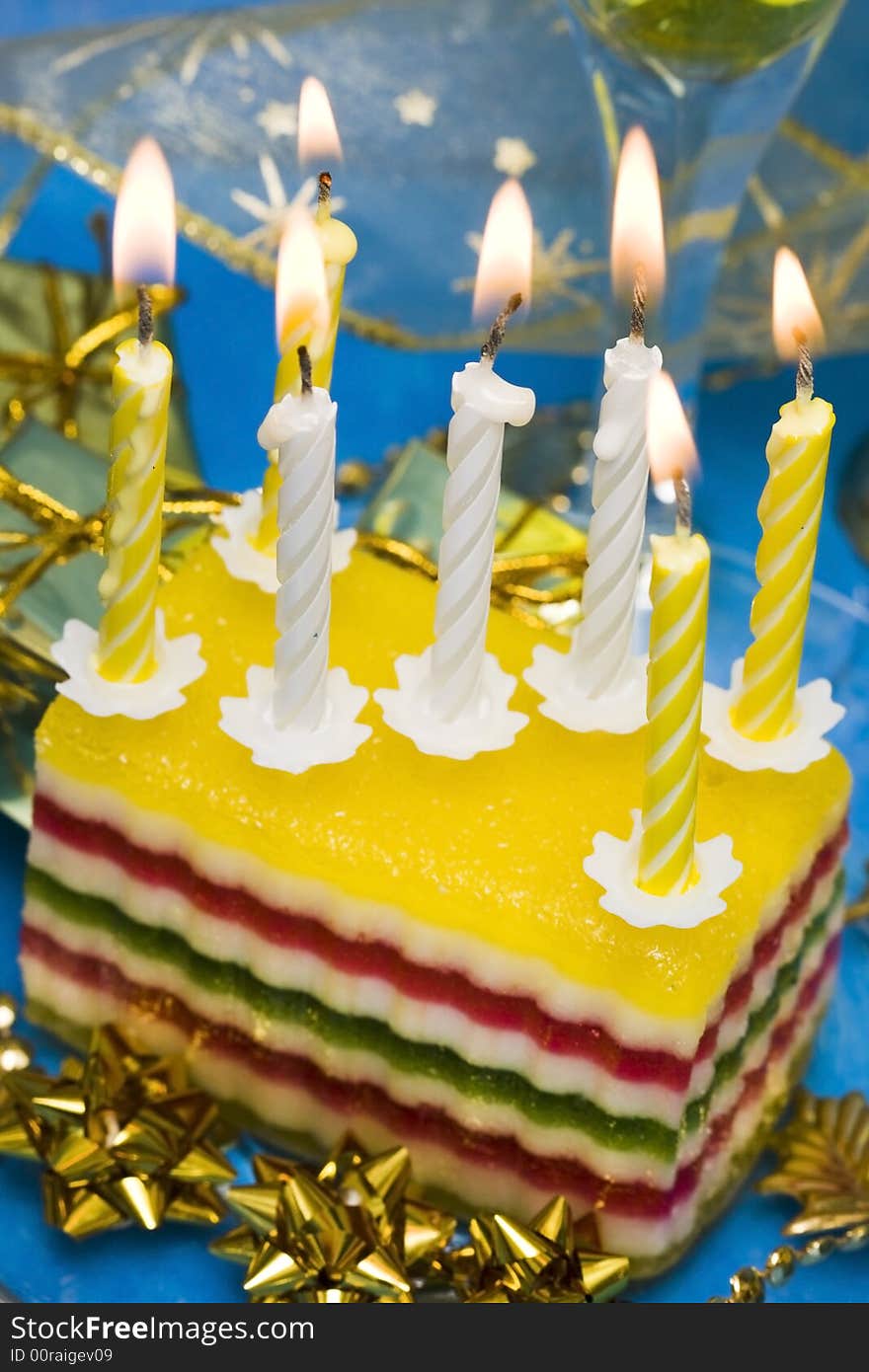 Celebratory table (cake and candles, two glasses with champagne, gift boxes) on blue