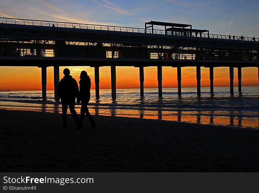 Pair walking on the beach watching sunset on Dutch seaside, Scheveningen. Pair walking on the beach watching sunset on Dutch seaside, Scheveningen