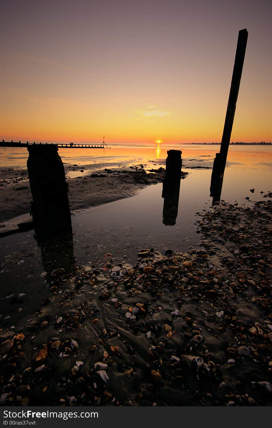 Sun setting on a West Wittering beach with groyns in the foreground. Sun setting on a West Wittering beach with groyns in the foreground