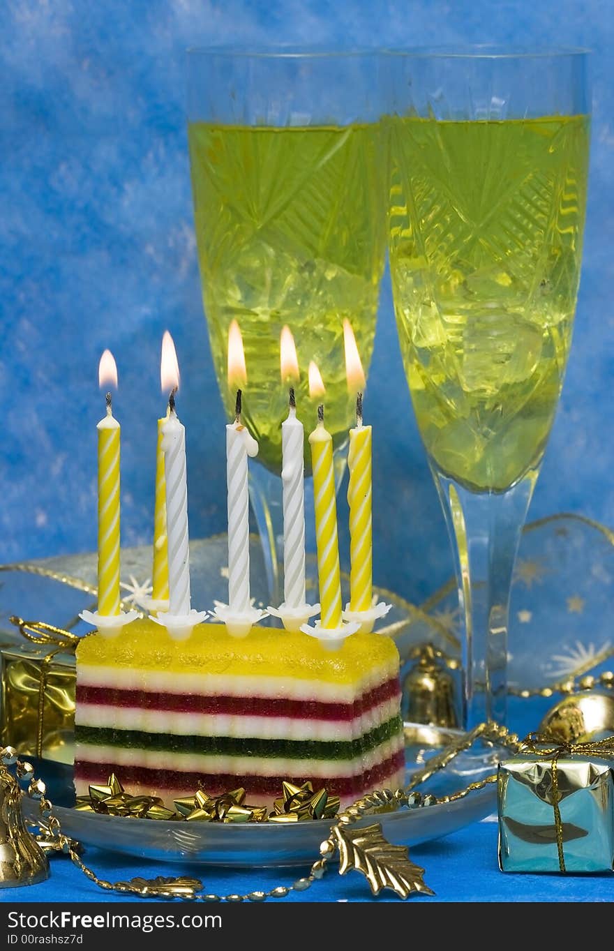 Celebratory table (cake and candles, two glasses with champagne, gift boxes) on blue