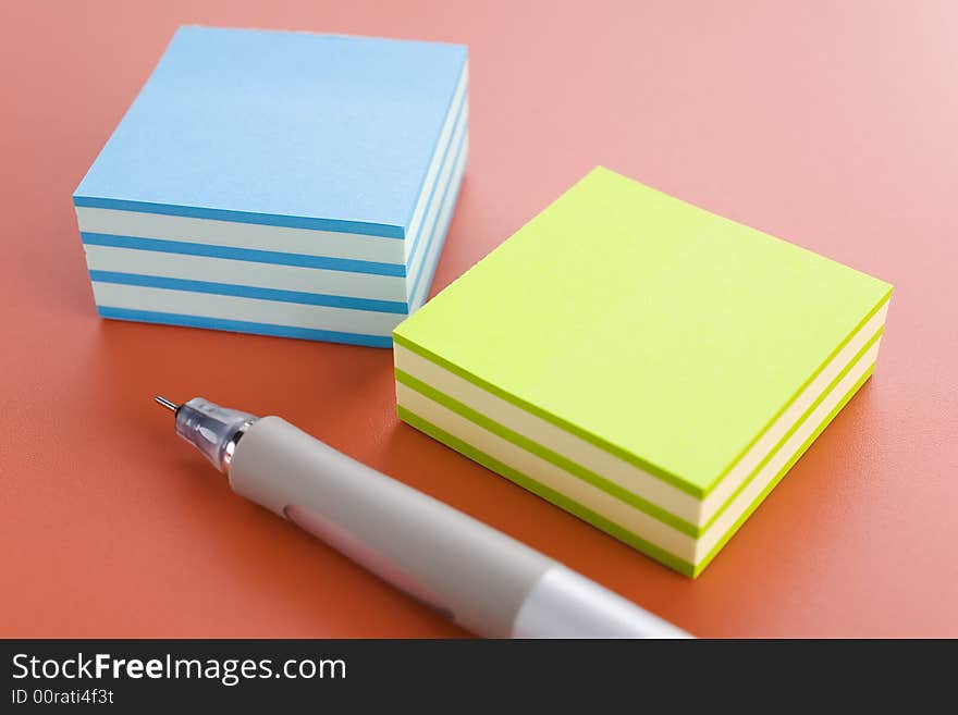 Piles of sticky notes and pen over a pink table