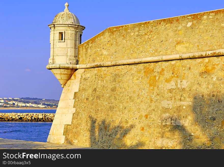 Portugal, area of Algarve, Lagos: typical architecture. Blue sky and yellow stone fortress; detail of one tower of control. Portugal, area of Algarve, Lagos: typical architecture. Blue sky and yellow stone fortress; detail of one tower of control