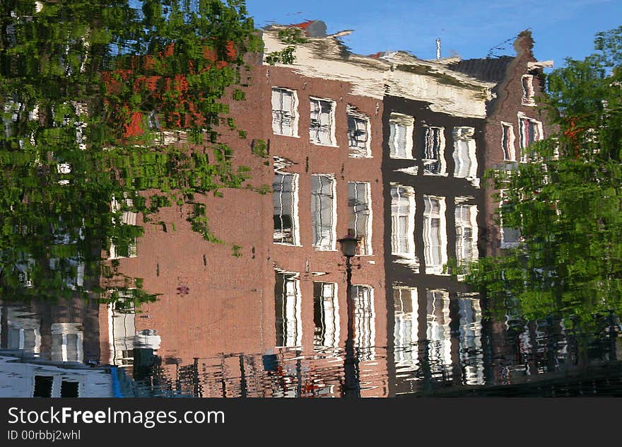 Amsterdam buildings reflected on a canal.