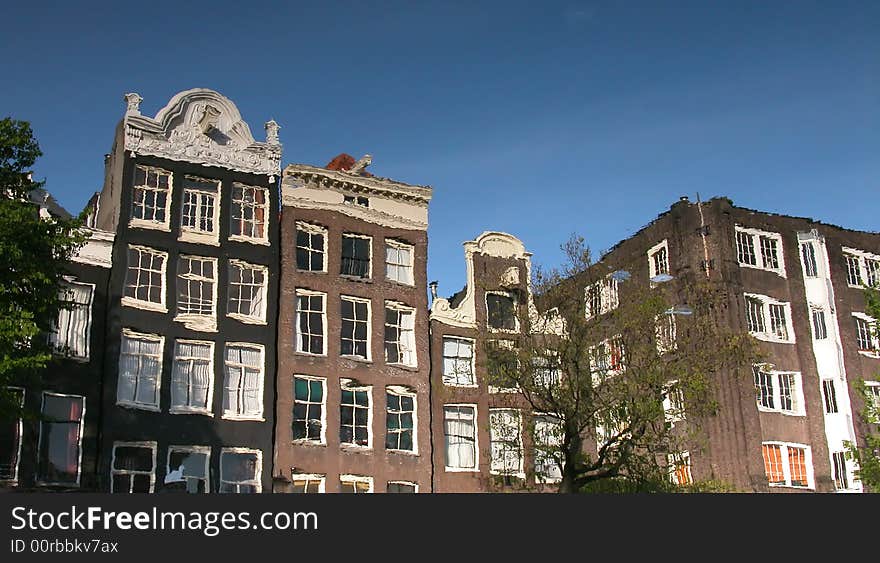 Amsterdam buildings reflected on a canal.