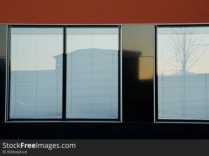 Modern office building. Reflection of another house and a tree on the sunset. Modern office building. Reflection of another house and a tree on the sunset.