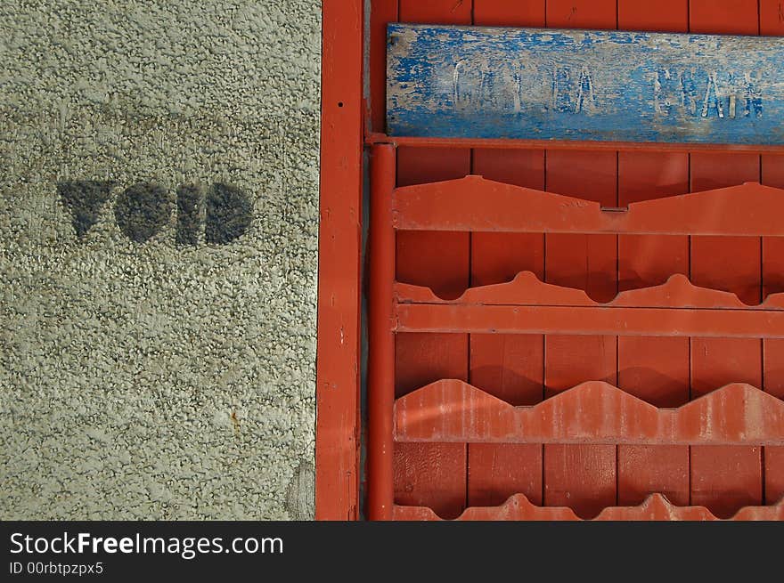 A fragment of wall offers a contrast of colors and textures: grey stucco, faded red metal, and weathered blue wood. The cryptic word VOID adds to the mystery. A fragment of wall offers a contrast of colors and textures: grey stucco, faded red metal, and weathered blue wood. The cryptic word VOID adds to the mystery.