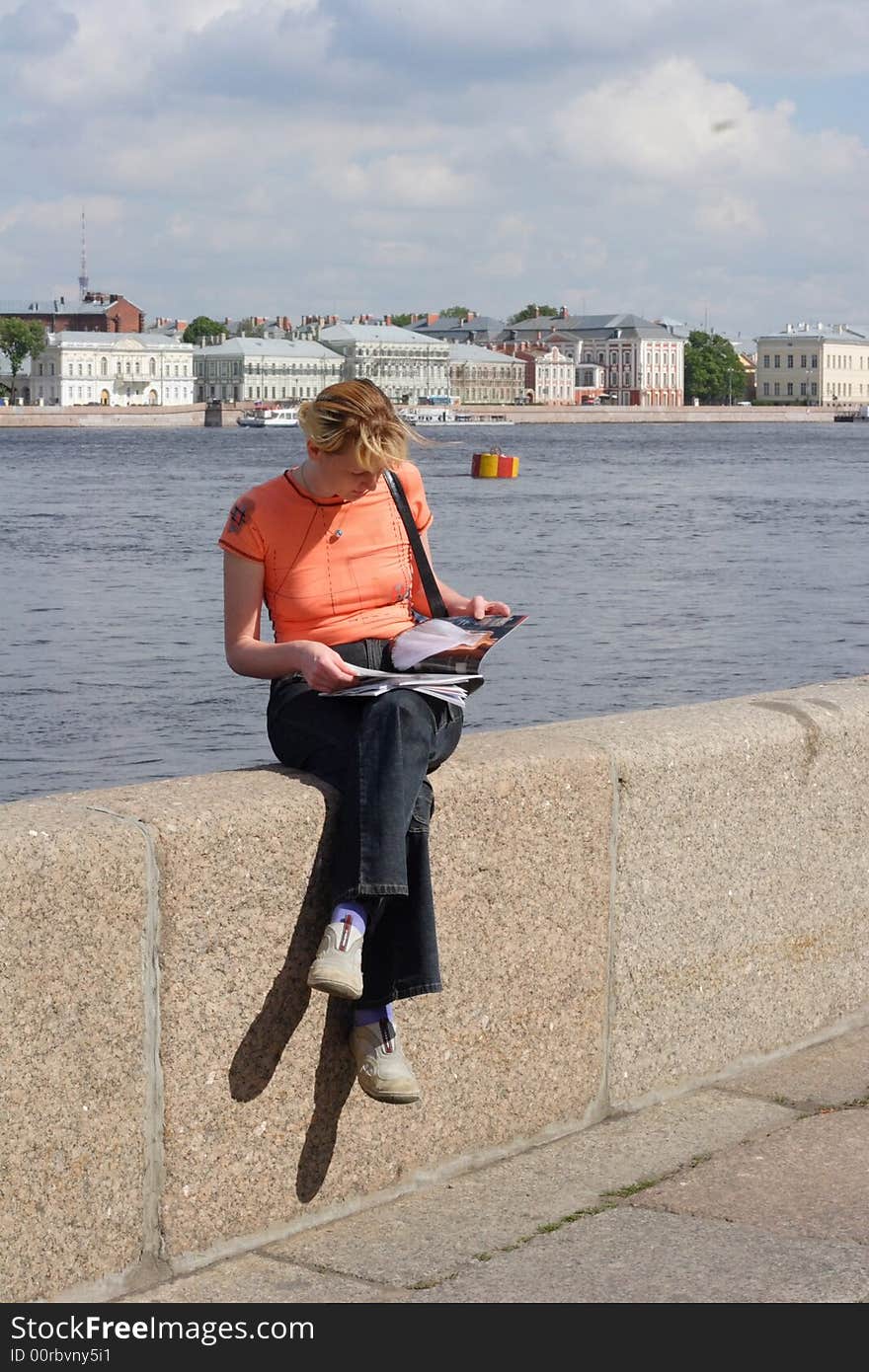 Girl reading magazine on canal border in Saint Petersburg