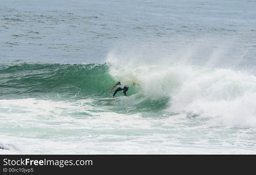 A surfer surfing out of a big wave about to dump him. A surfer surfing out of a big wave about to dump him