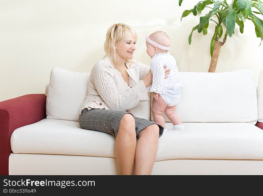 Mother and her baby girl on white sofa