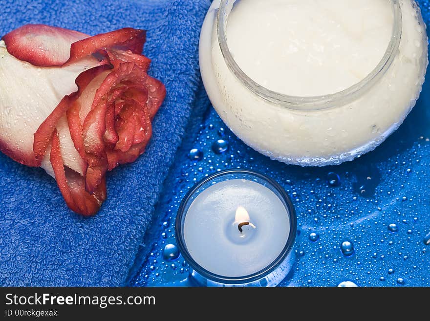 Cream, candle with rose on blue background