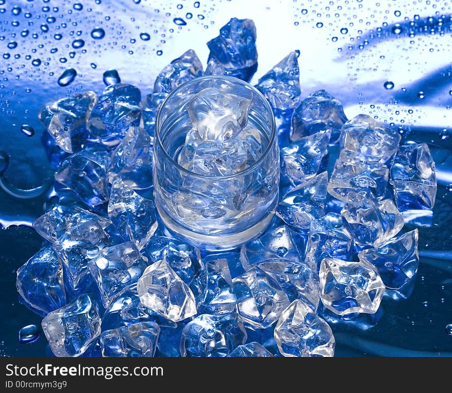 Glass with water and ice over blue