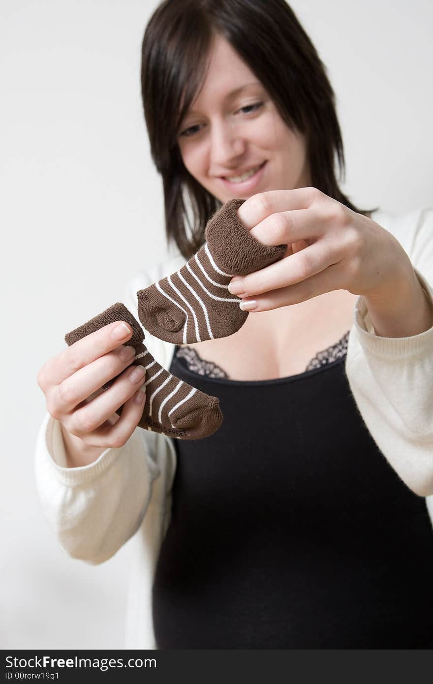 Pregnant woman holding up baby socks. Pregnant woman holding up baby socks