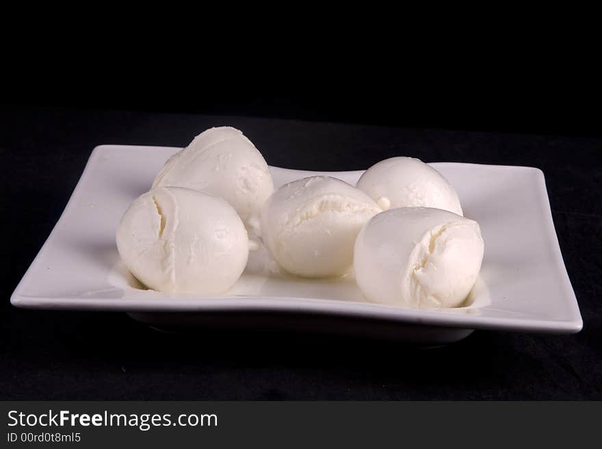 Balls of fresh, semi-soft buffalo mozzarella cheese on a white plate. Balls of fresh, semi-soft buffalo mozzarella cheese on a white plate.