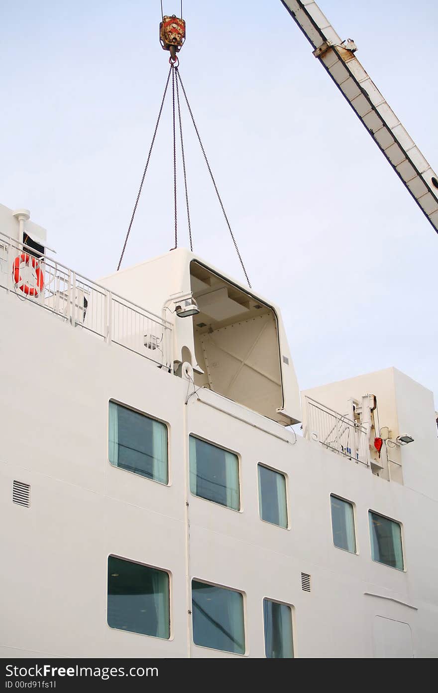 Crane lifting off the cover for the ships life raft system in order to replace it.