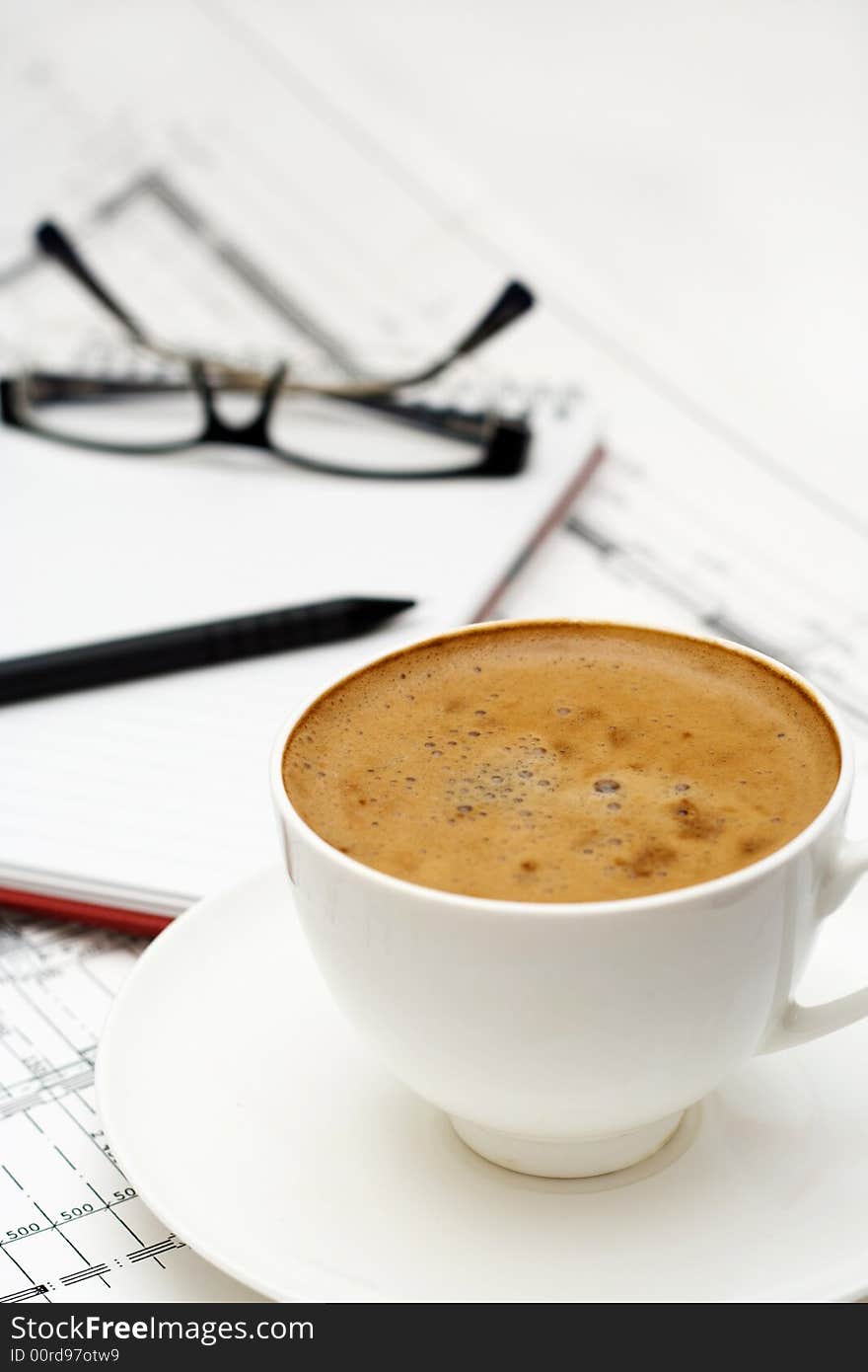 Cup of coffee with notepad and glasses.