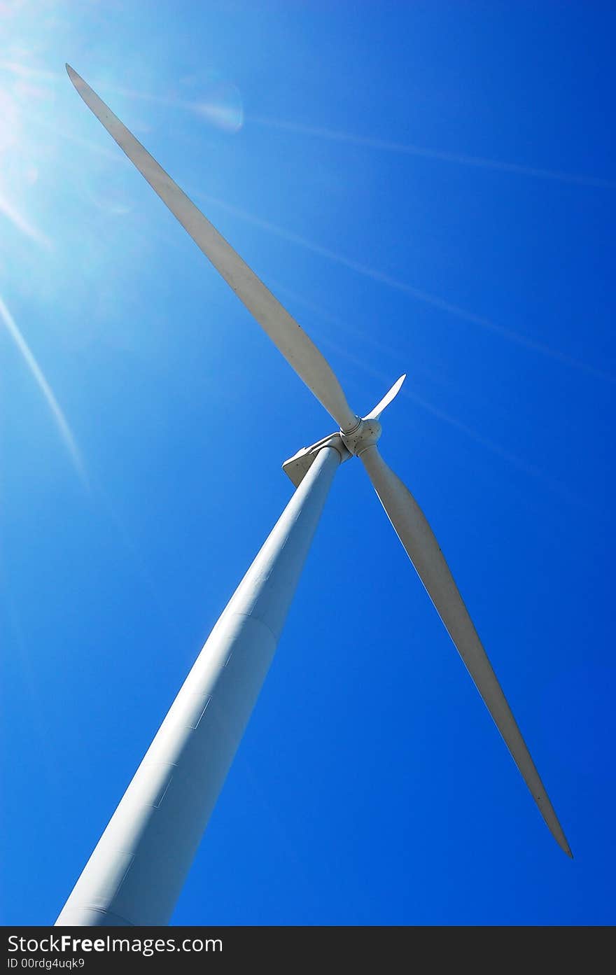 Wind turbine with sun flare on sky background