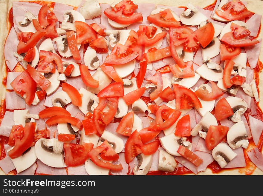 Home-made pizza with ham, tomatoes and mushrooms. Ready for cooking. Home-made pizza with ham, tomatoes and mushrooms. Ready for cooking