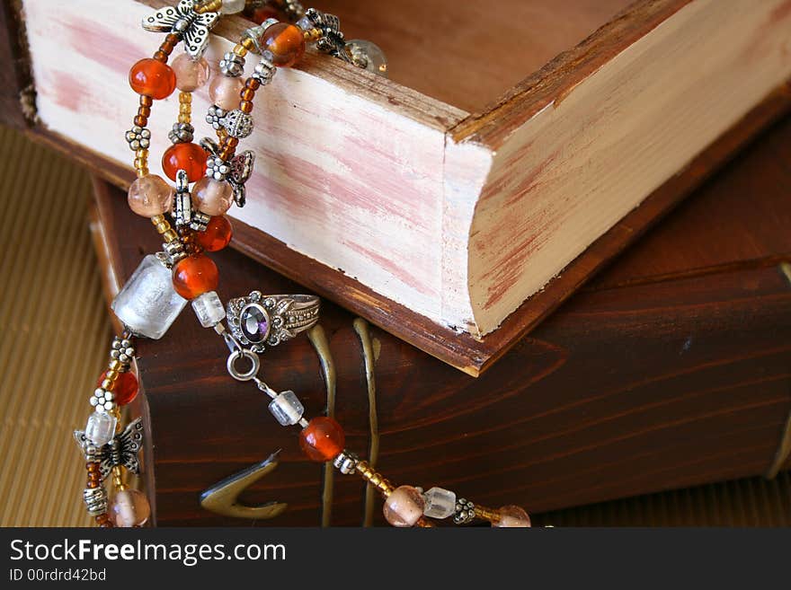 Orange Jewellery hanging from an open wooden jewellery box and a purple stone ring. Orange Jewellery hanging from an open wooden jewellery box and a purple stone ring