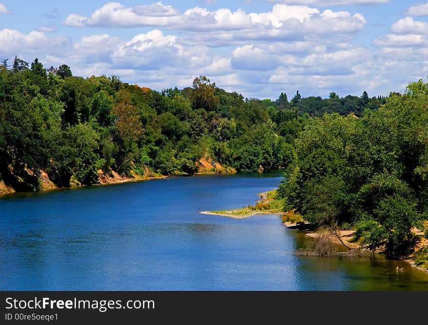 Lots of white clouds over a clean blue river with lots of trees around it
. Lots of white clouds over a clean blue river with lots of trees around it