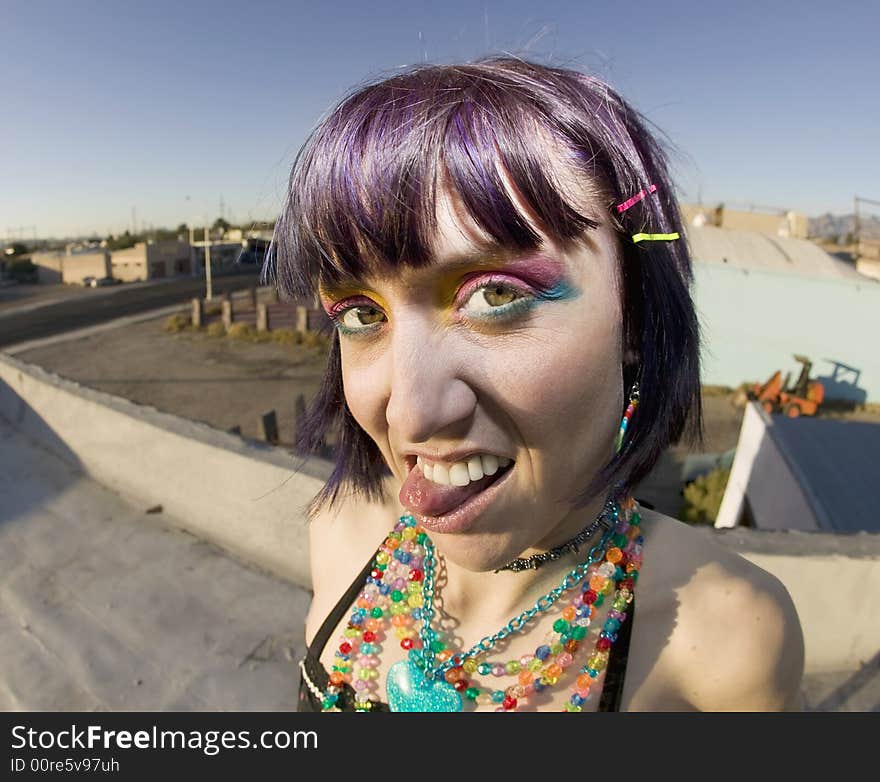 Fisheye shot of young woman sticking out her tongue on a roof. Fisheye shot of young woman sticking out her tongue on a roof