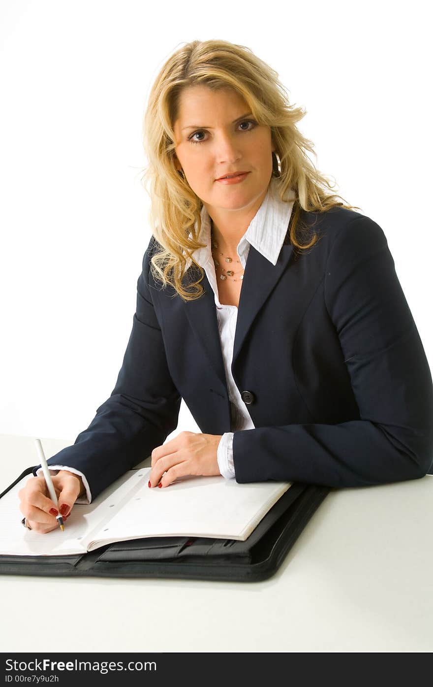 Blonde business woman sitting at desk taking notes in folio. Blonde business woman sitting at desk taking notes in folio