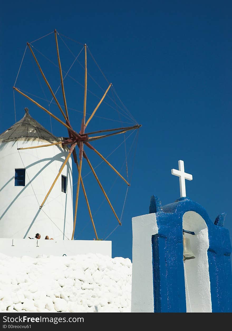 Old windmill and belltower in sunny Santorini