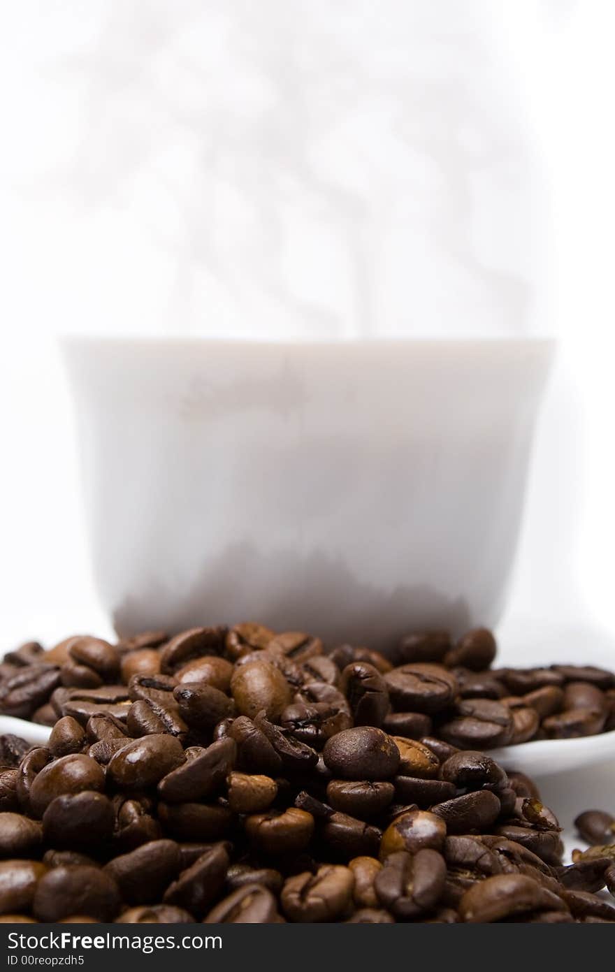 The cup of coffee and coffee beans scattered around. The cup of coffee and coffee beans scattered around