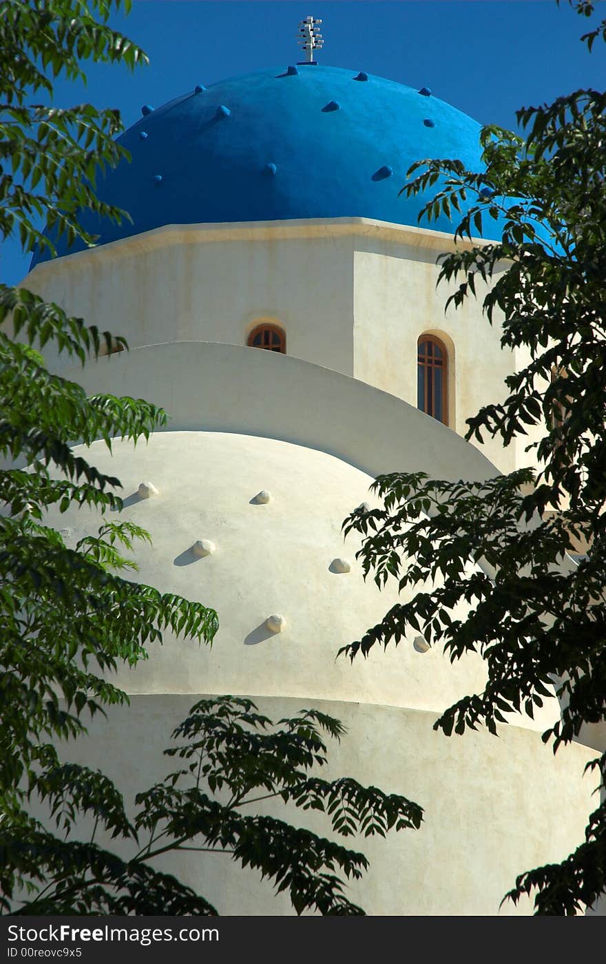 Blue domed church behind trees in sunny Santorini. Blue domed church behind trees in sunny Santorini