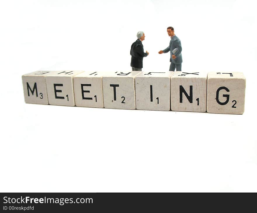 A couple of businessmen or managers standing behind the spelled out word meeting