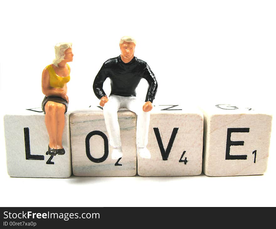 Two figurines sitting on the word love