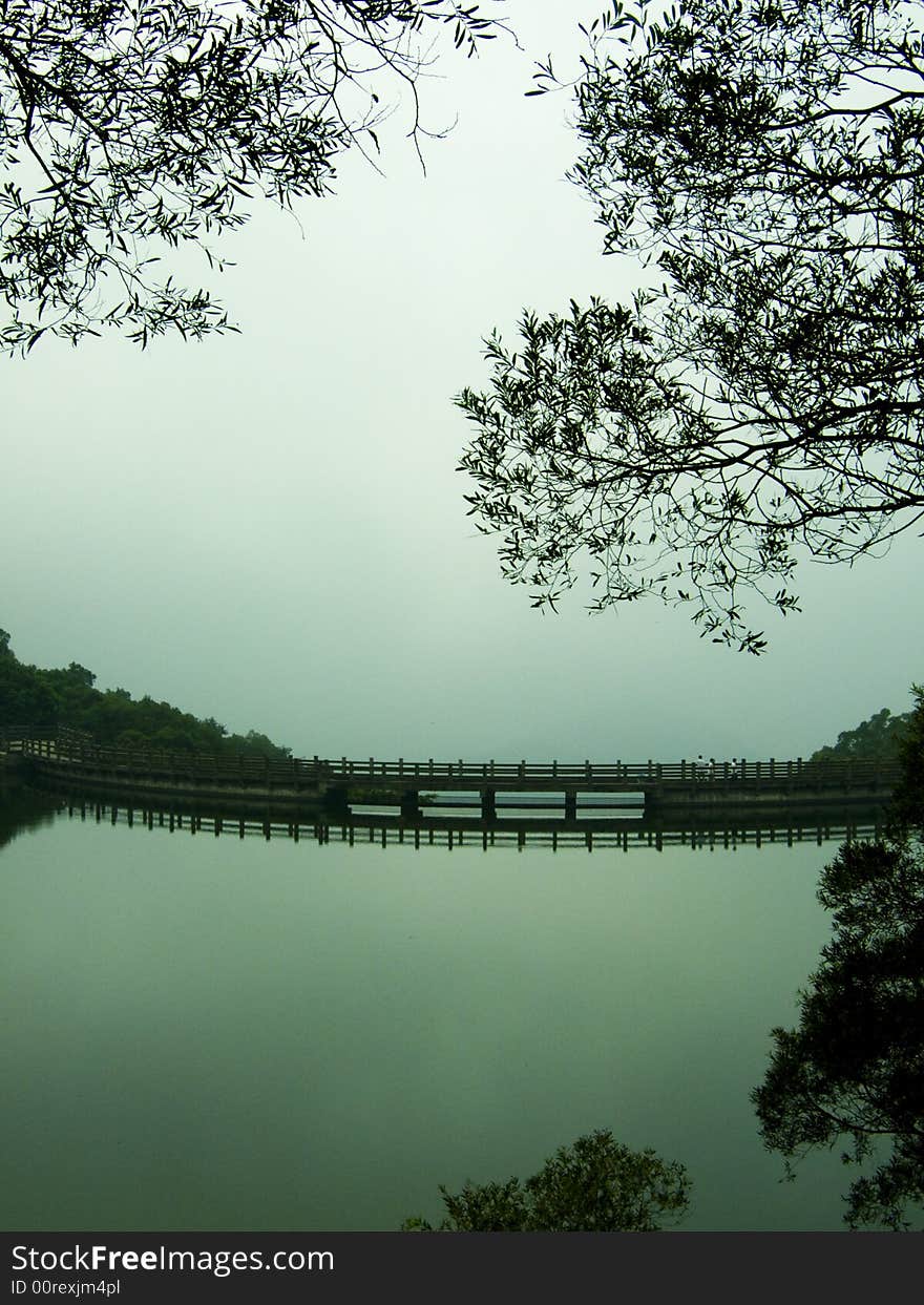 A lake with bridge and tree after rain. A lake with bridge and tree after rain