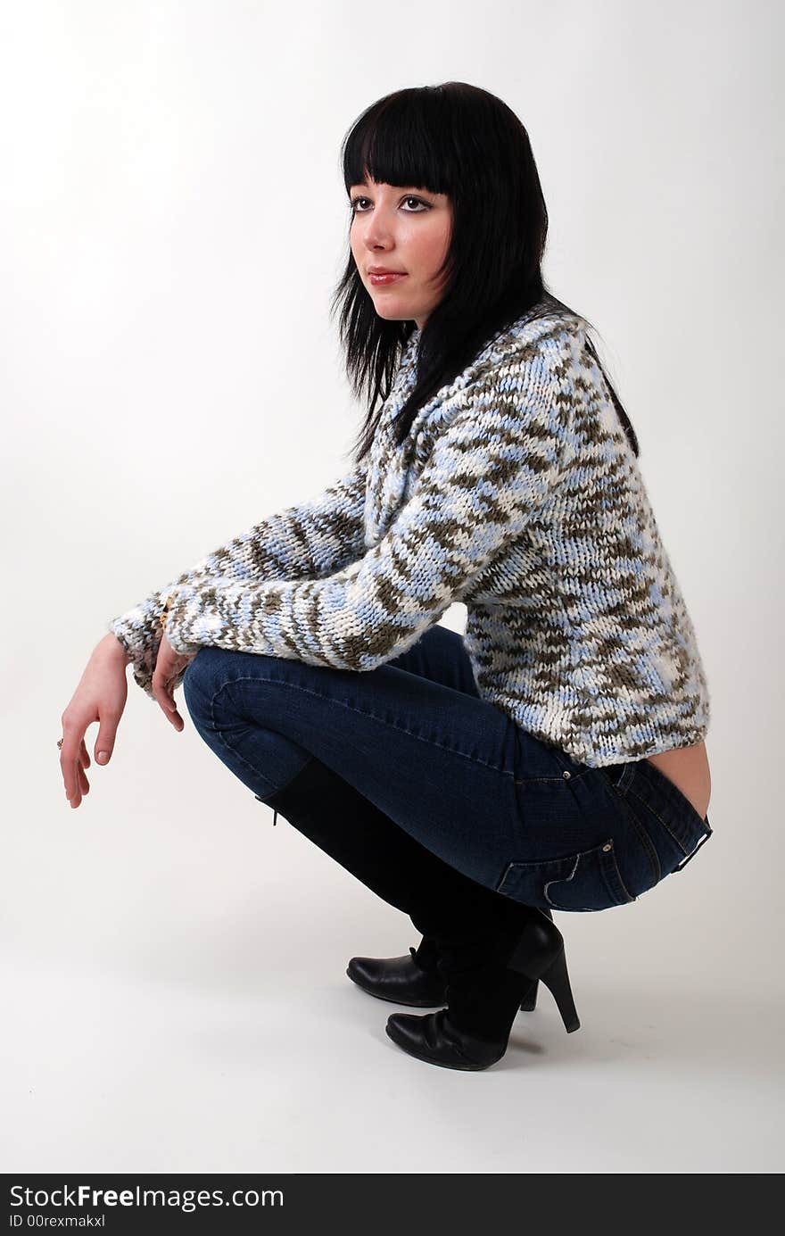 Young beautiful girl in jeans and sweater sitting in studio. Young beautiful girl in jeans and sweater sitting in studio