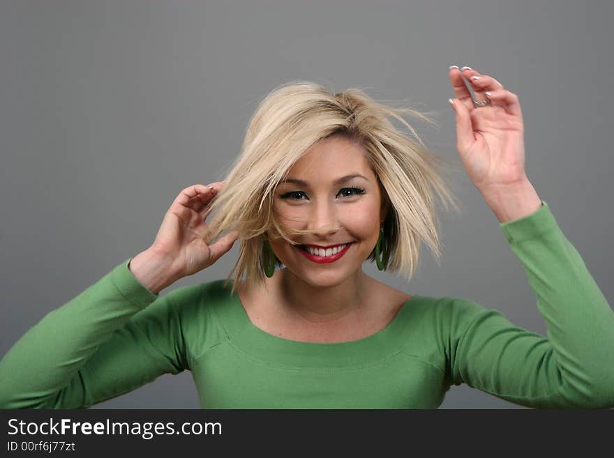 A blonde fashion model in green blouse messing up her hair. A blonde fashion model in green blouse messing up her hair