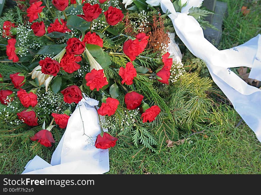 A bouquet of roses is laid on a new grave. A bouquet of roses is laid on a new grave