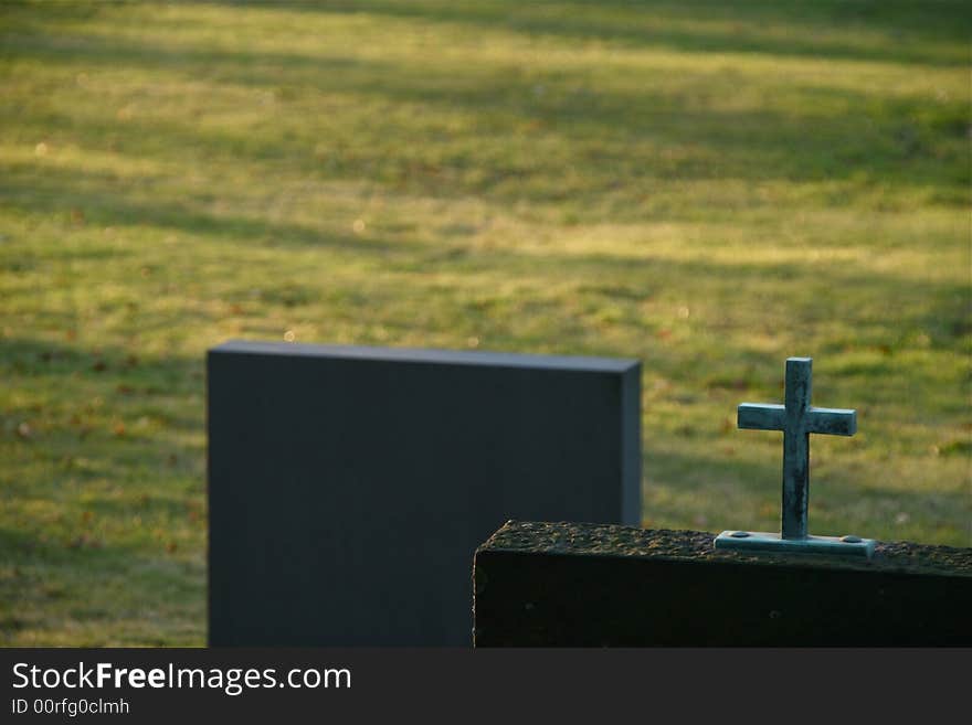 Two gravestone on a graveyard field. A cross. Two gravestone on a graveyard field. A cross