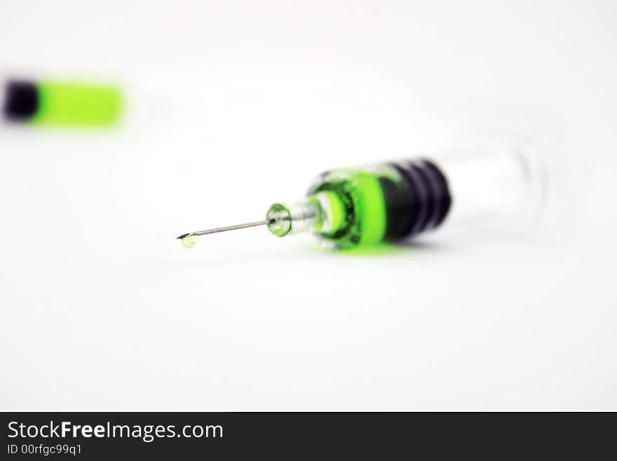 Syringe with green substance incide on white