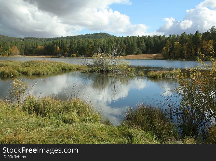 Autumn landscape. Lake in forest with reflection of clouds