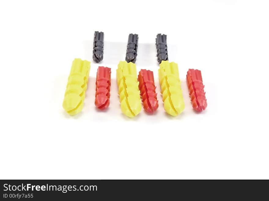 Three red,yellow and grey wall-plugs on a white background. Three red,yellow and grey wall-plugs on a white background