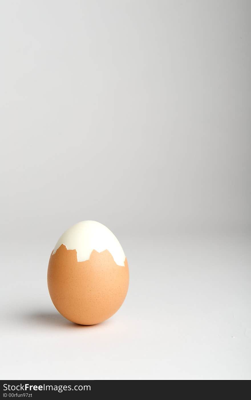 Partially peeled hard boiled egg on neutral background Think outside of the box. Partially peeled hard boiled egg on neutral background Think outside of the box