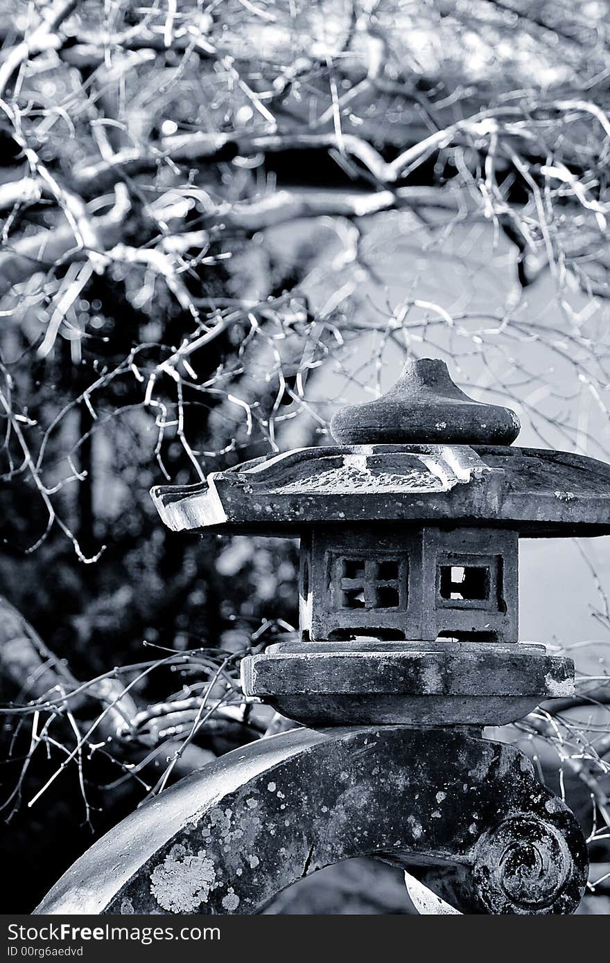 Cool toned black and white photo of a stone lantern in a Japanese garden.