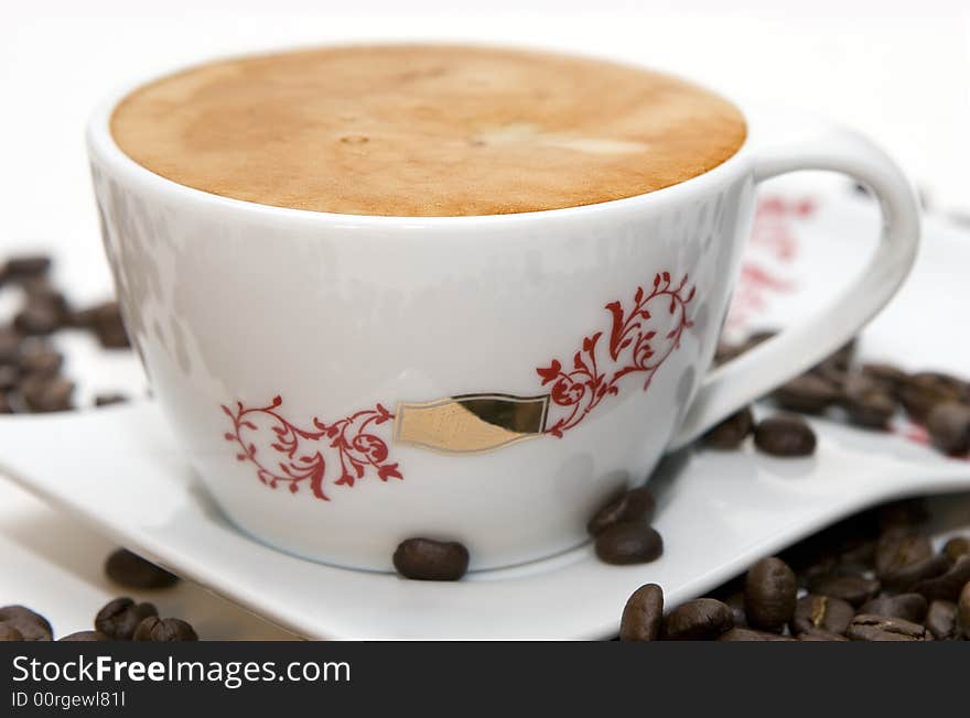 Cup of coffee and grains over white