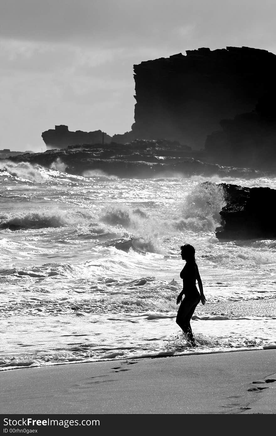 Black and white photograph of a woman going for a swim in the rough waters of Sandy Beach, on the South Shore of Oahu, Hawaii. Black and white photograph of a woman going for a swim in the rough waters of Sandy Beach, on the South Shore of Oahu, Hawaii