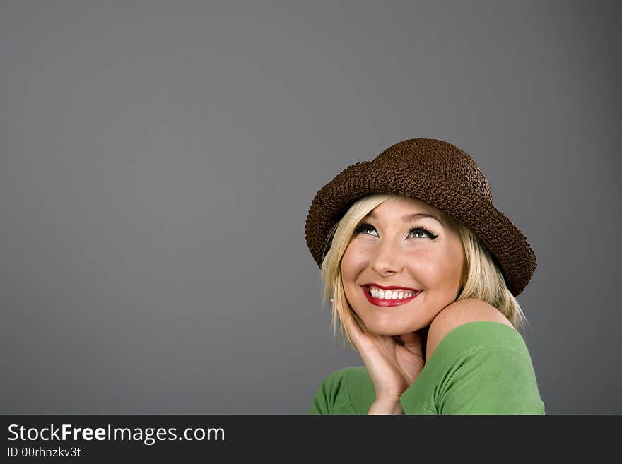 A blonde model in a brown hat smiling and looking up. A blonde model in a brown hat smiling and looking up